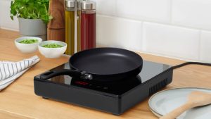 La cuisinière portable à 75 $ d’IKEA éloigne la chaleur, la graisse et les odeurs de cuisson de ma maison et transforme ma terrasse en cuisine extérieure A black single burner electric stovetop on a wooden kitchen counter with a black pan on top.
