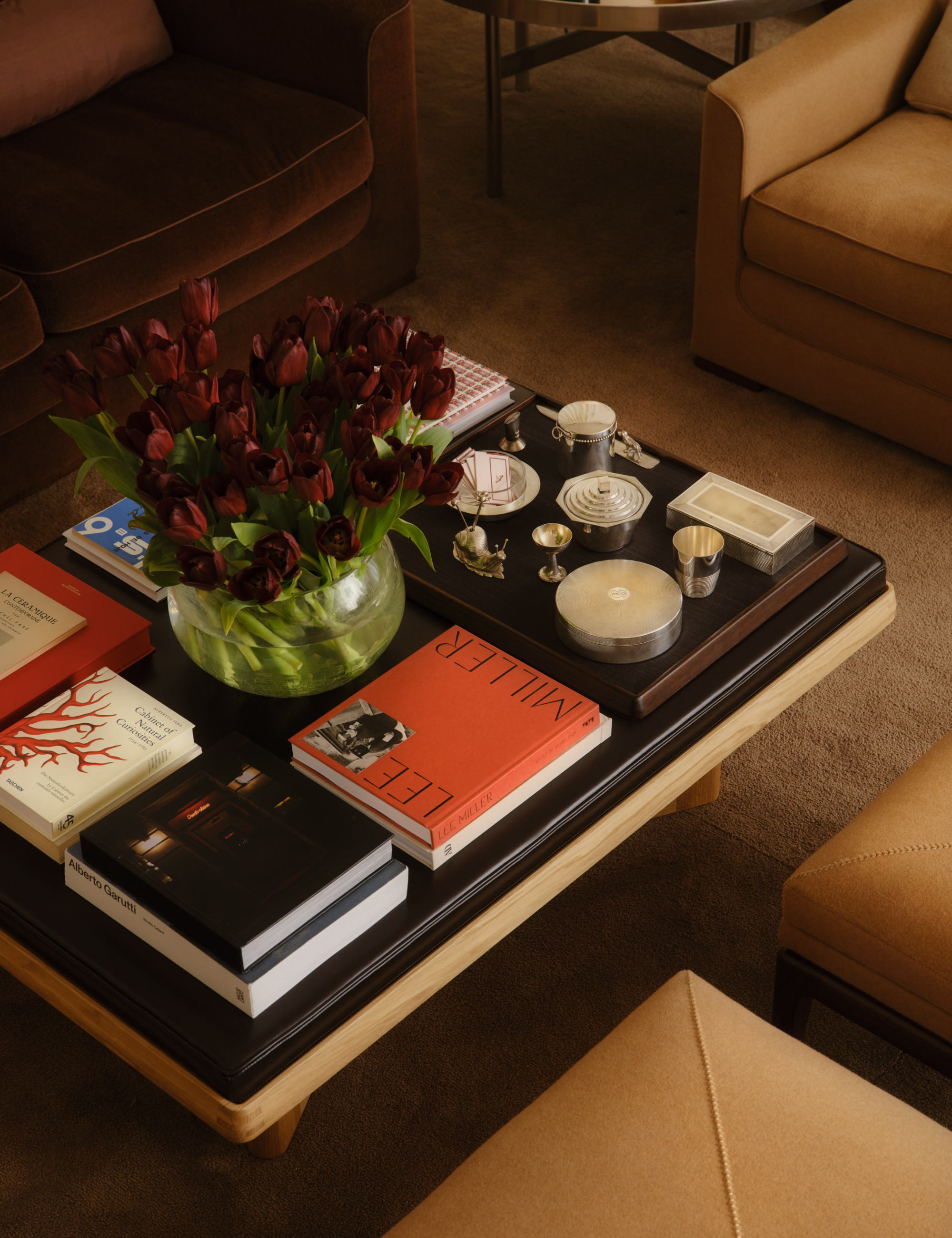 : table basse avec plateau en cuir ornée de piles de livres et d'objets assortis