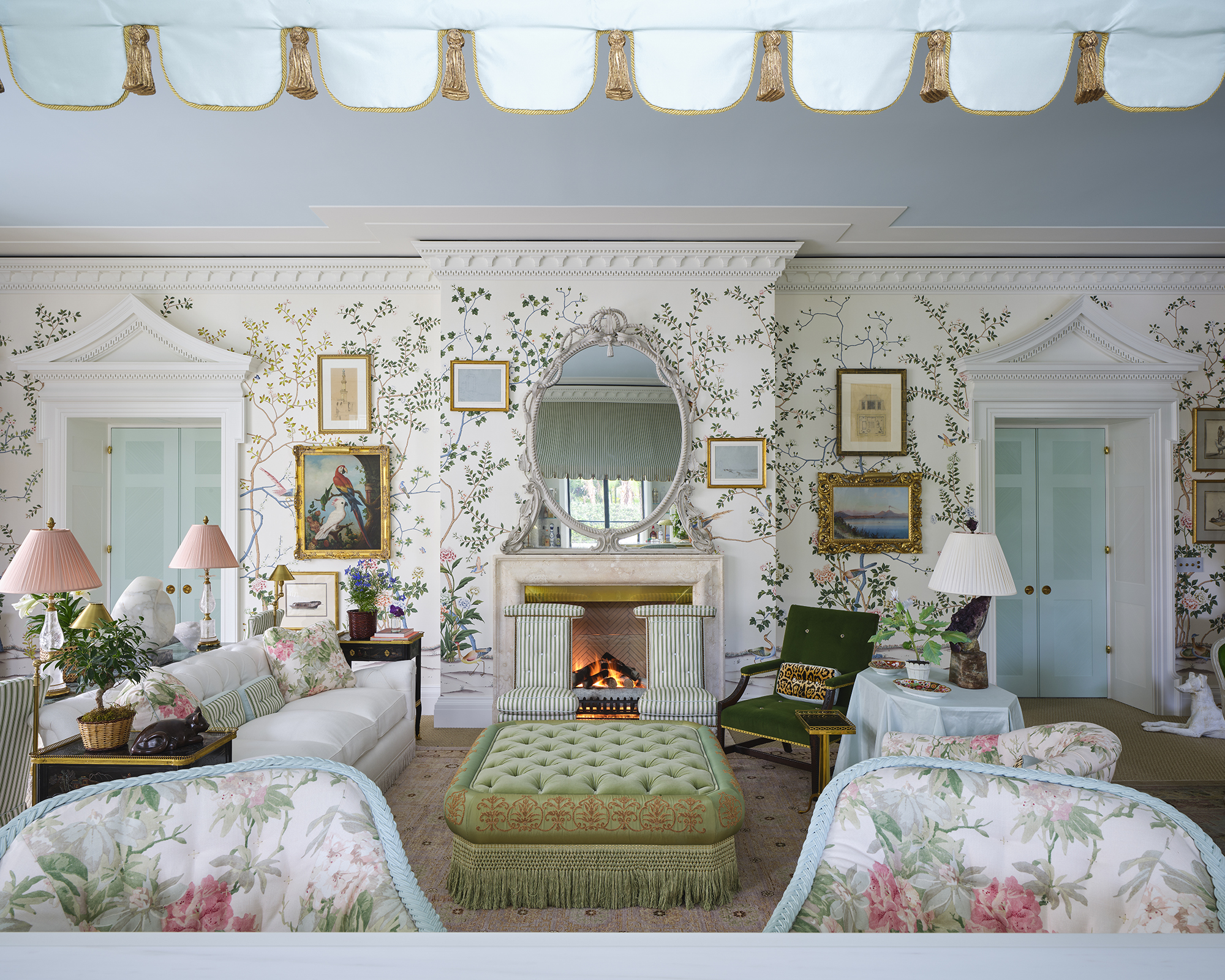 grand salon aux murs blancs recouverts d'un motif botanique et aux plafonds bleu poudré. Les meubles sont disposés de manière symétrique