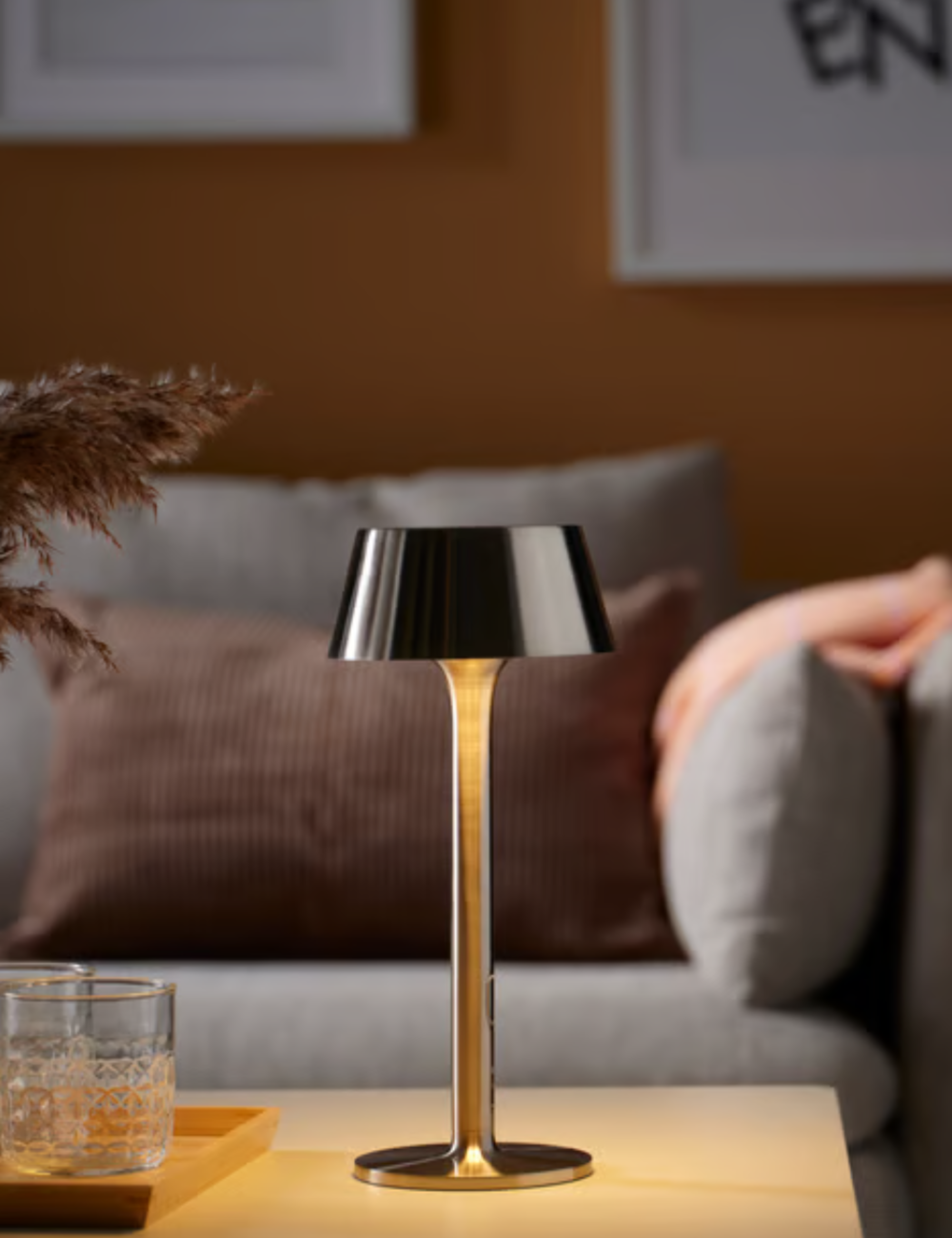 Lampe portable intérieure/extérieure Chrome IKEA posée sur une table basse en bois à côté d'un plateau de verres en cristal taillé