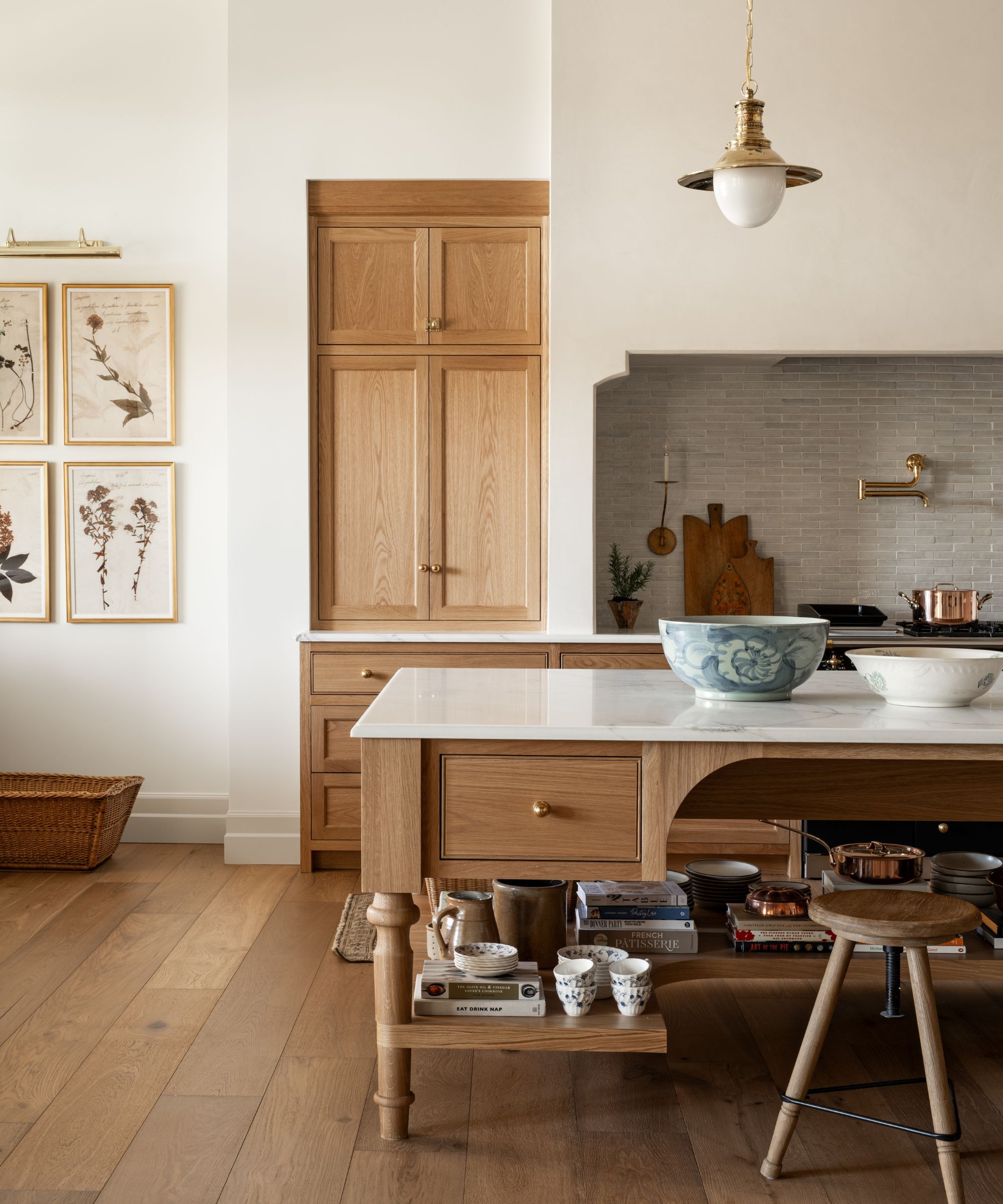 une cuisine en chêne superposé du Studio McGee avec un grand îlot surmonté de marbre, une hotte galbée et une décoration vintage