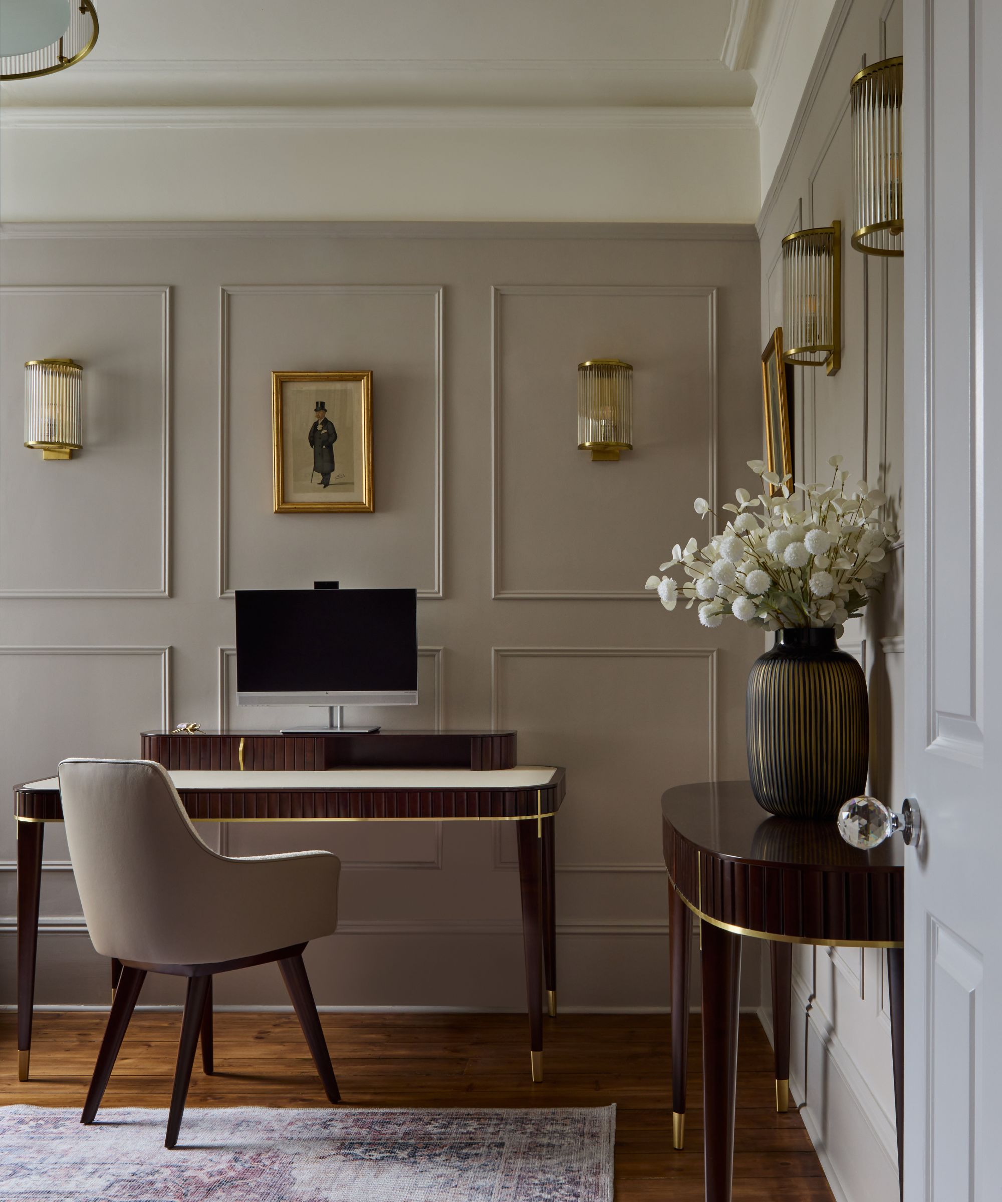 Bureau à domicile avec Elephant's Breath de Farrow &amp; Murs peints en boule, lambris muraux, un bureau en bois sombre avec une chaise de bureau en velours gris et une console en bois assortie avec un vase de fleurs.