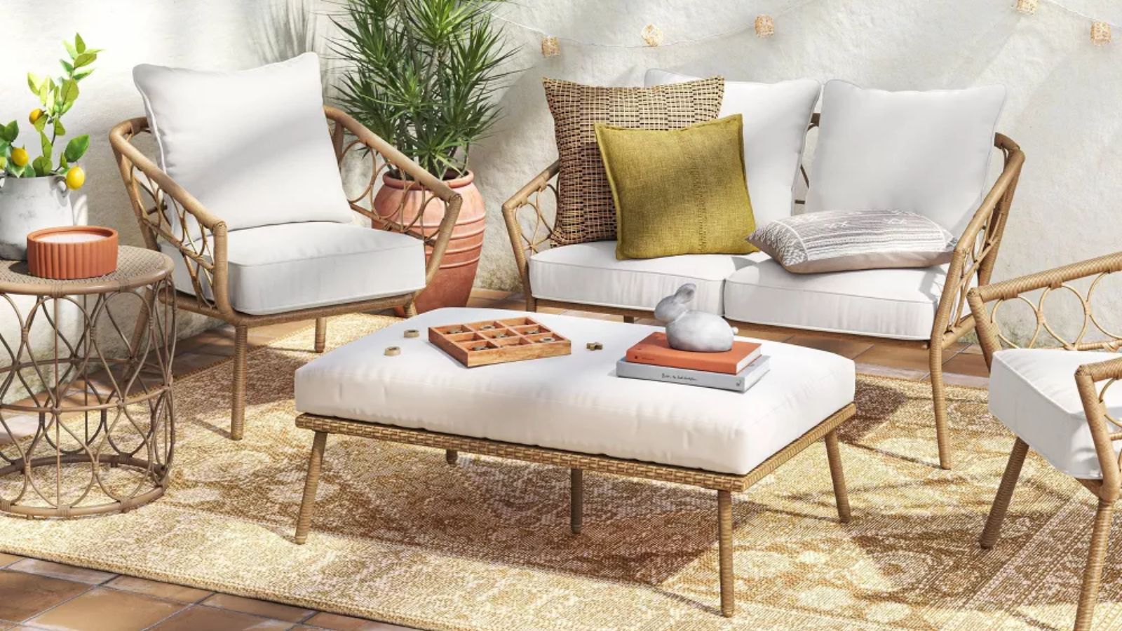 meubles de patio en osier et rotin avec petite causeuse, deux fauteuils de baignoire et un pouf posés sur un tapis beige de style vintage 