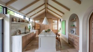 Découvrez comment une étable en ruine a reçu une nouvelle vie en tant que cuisine familiale intemporelle qui honore toujours ses humbles débuts A converted barn turned into a large kitchen with vaulted ceilings, a neutral color palette, and wooden accents