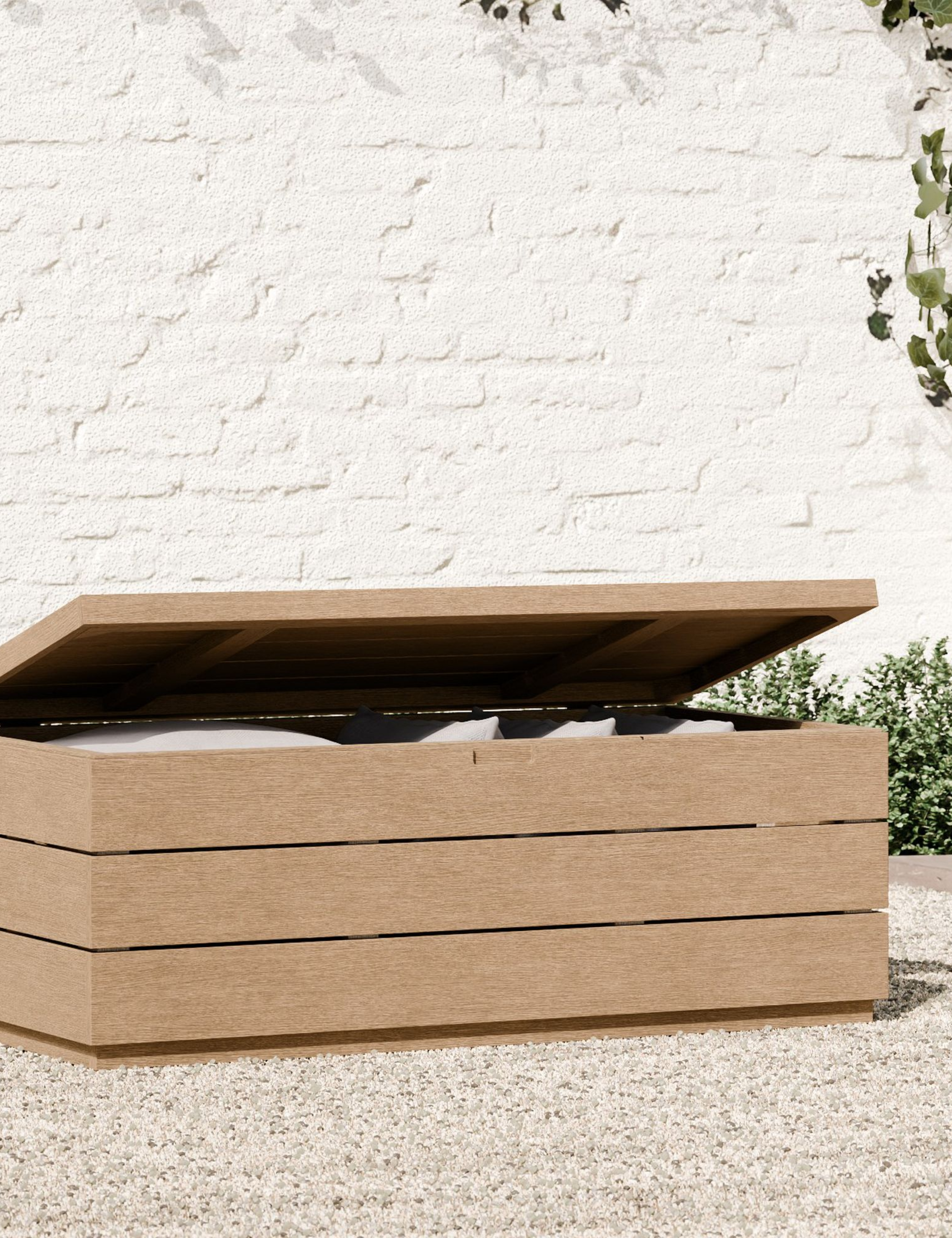 Coffre de rangement extérieur en bois West Elm vu avec son couvercle relevé, exposant les coussins de patio de rechange qu'il cache à l'intérieur