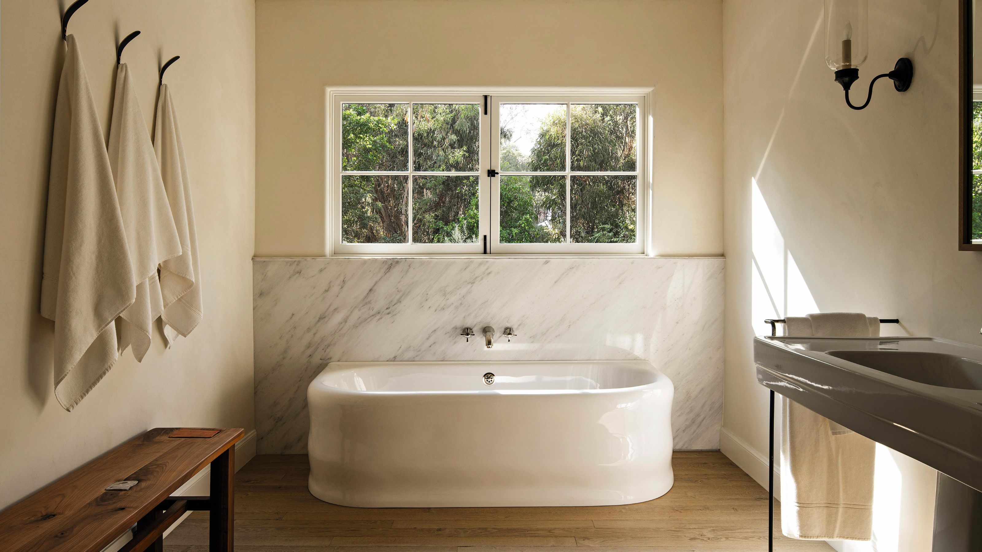 une salle de bains neutre et douce avec un dosseret incurvé autoportant et mable et un style simple