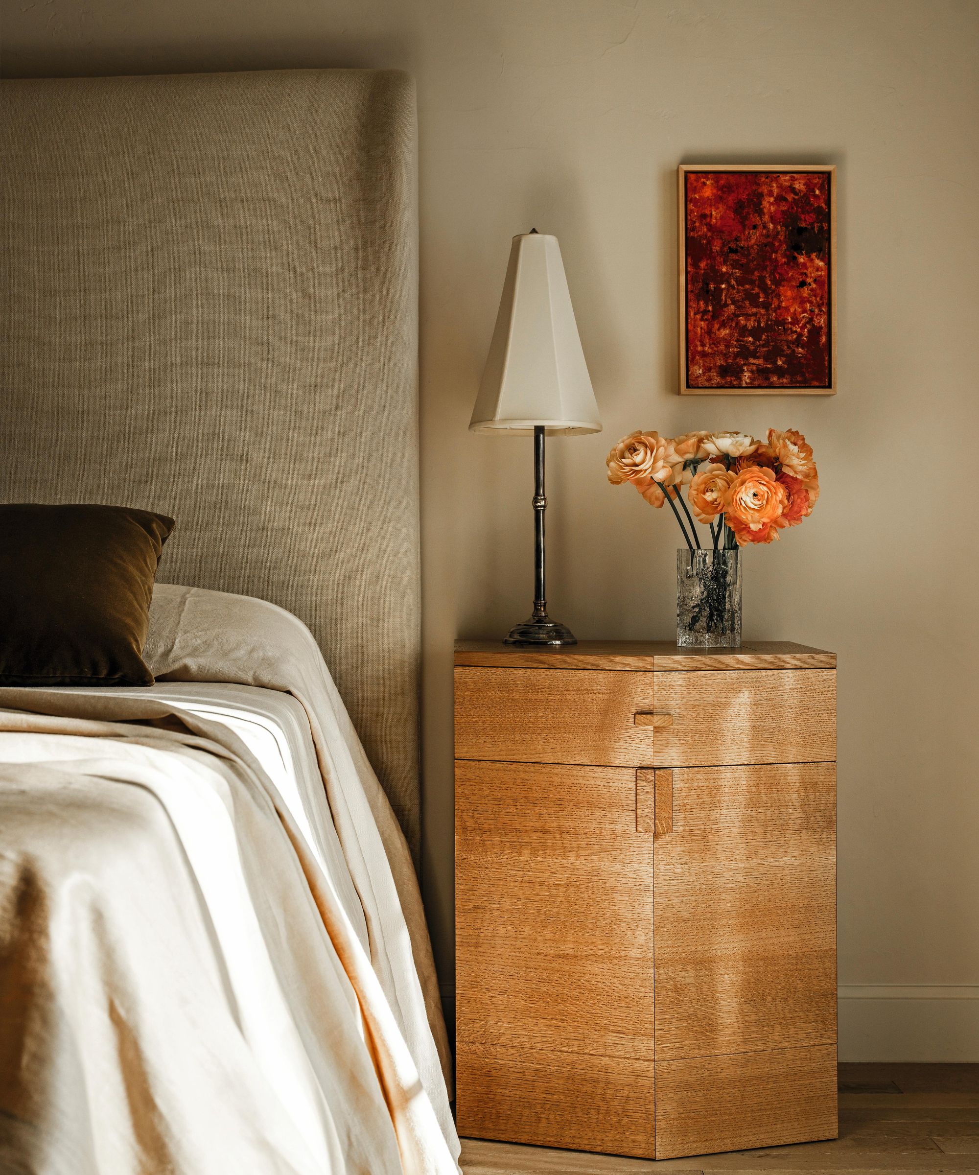 une chambre à coucher beige avec tête de lit en lin et table de nuit en bois de style art déco