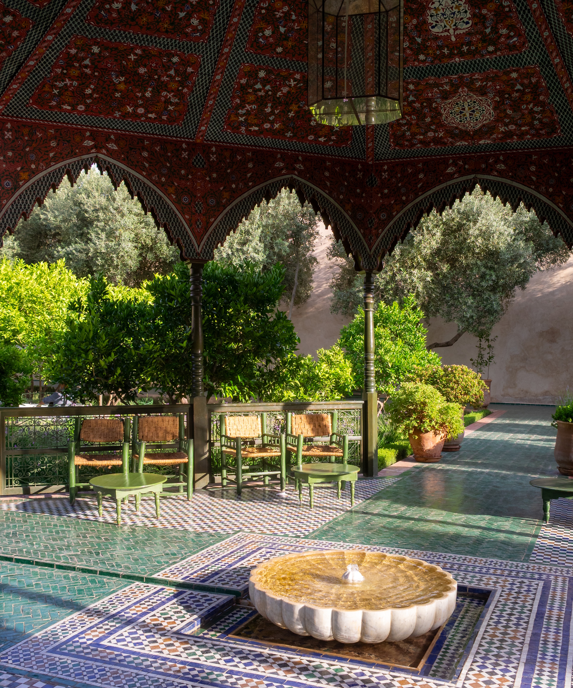 Cour marocaine avec fontaine bouillonnante festonnée et table et chaises vertes