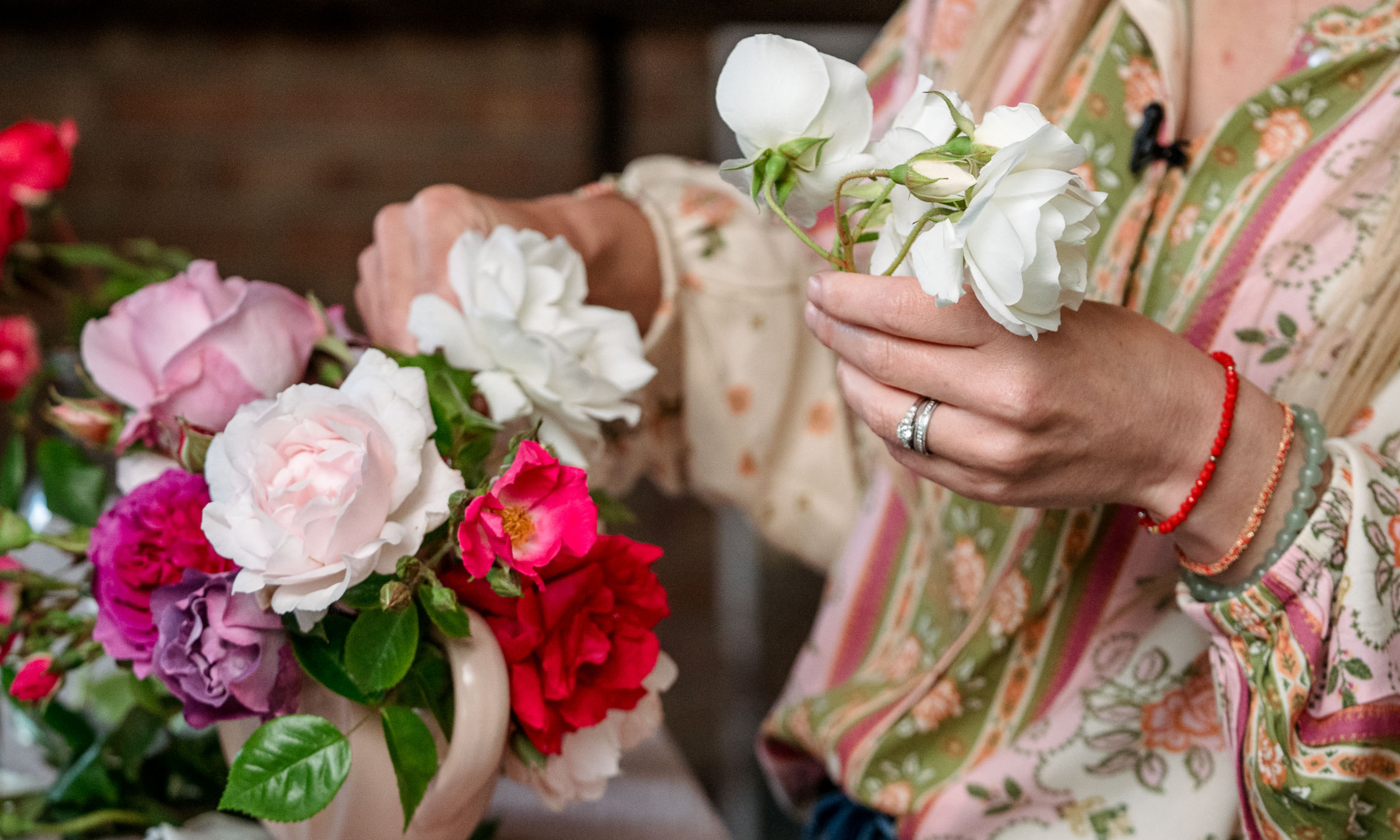 Mains faisant un motif floral rose de jardin dans un vase vintage rose