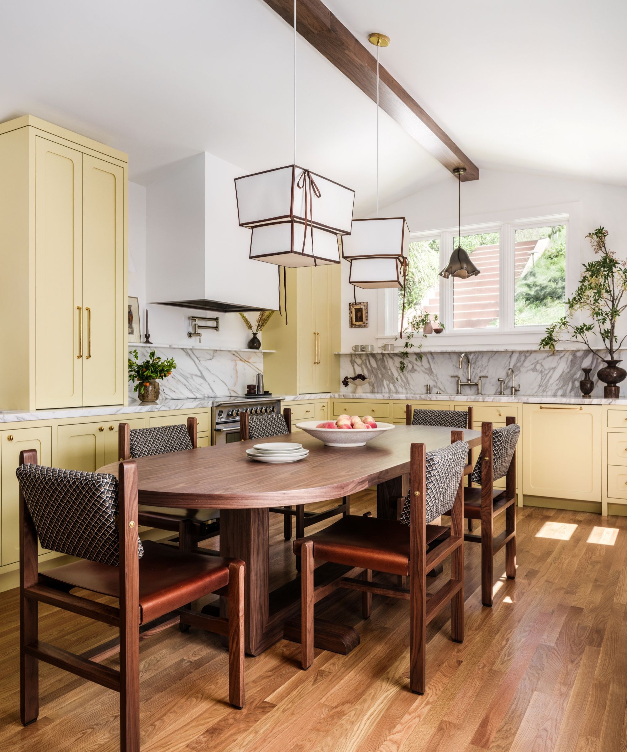 une cuisine jaune avec des comptoirs en marbre et une grande table en bois au centre