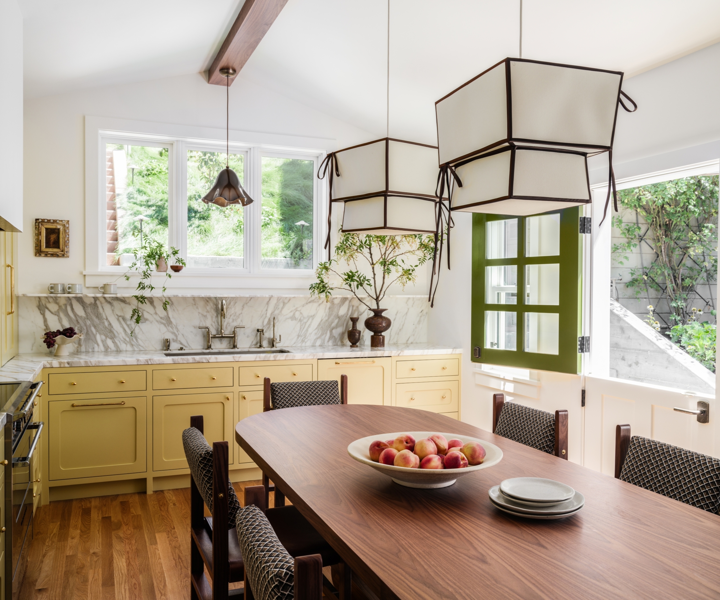 Une cuisine jaune avec une grande table en bois et des comptoirs en marbre