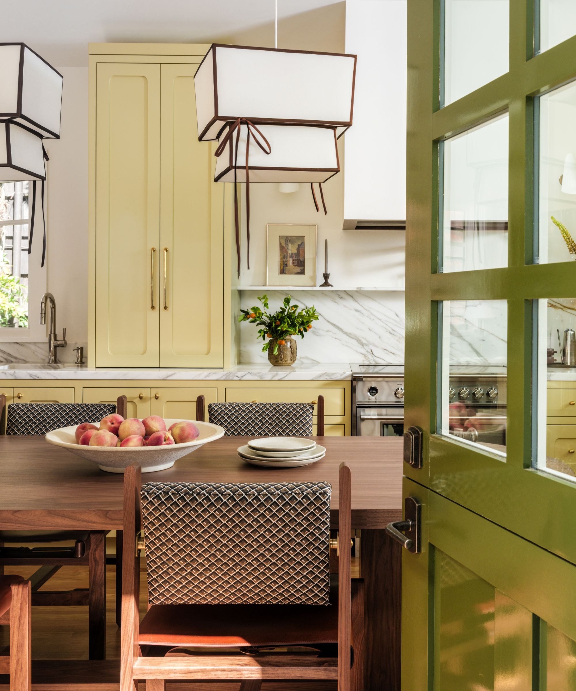 Une cuisine jaune avec des comptoirs en marbre, une table en bois et une porte hollandaise verte