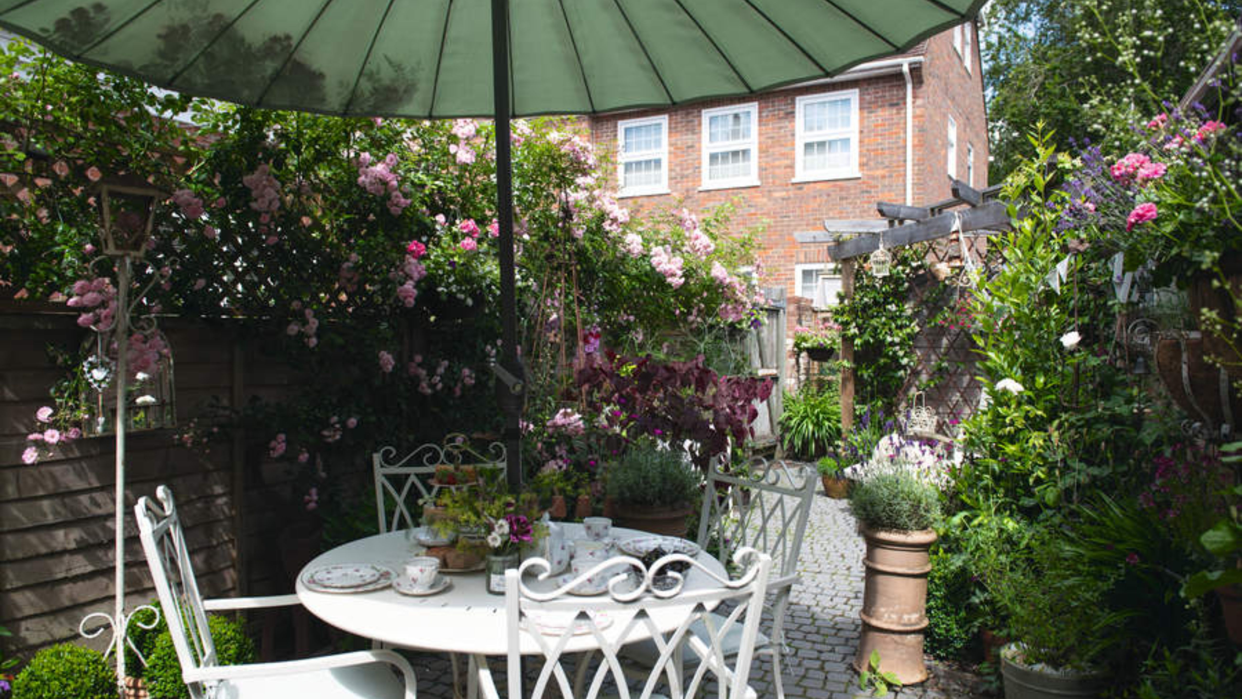 Charmant patio-jardin doté de mobilier d'extérieur de style ancien et d'un parasol vert
