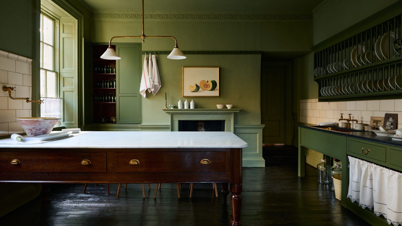 Cuisine verte deVOL Heirloom comprenant une table laitière autoportante avec un plan de travail en marbre, un rangement pour assiettes ouvertes, des armoires peintes, un parquet en bois sombre et des détails architecturaux d'époque.