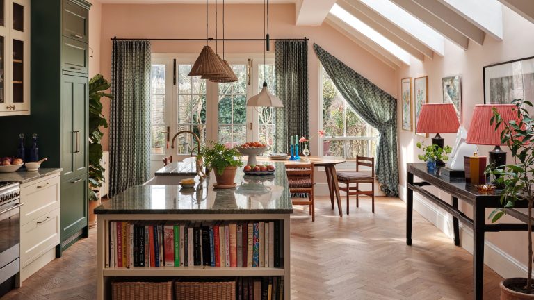 An open plan kitchen and ding space with a mix of green and white cabinets, a large island featuring a bookshelf, green countertops, and green curtains