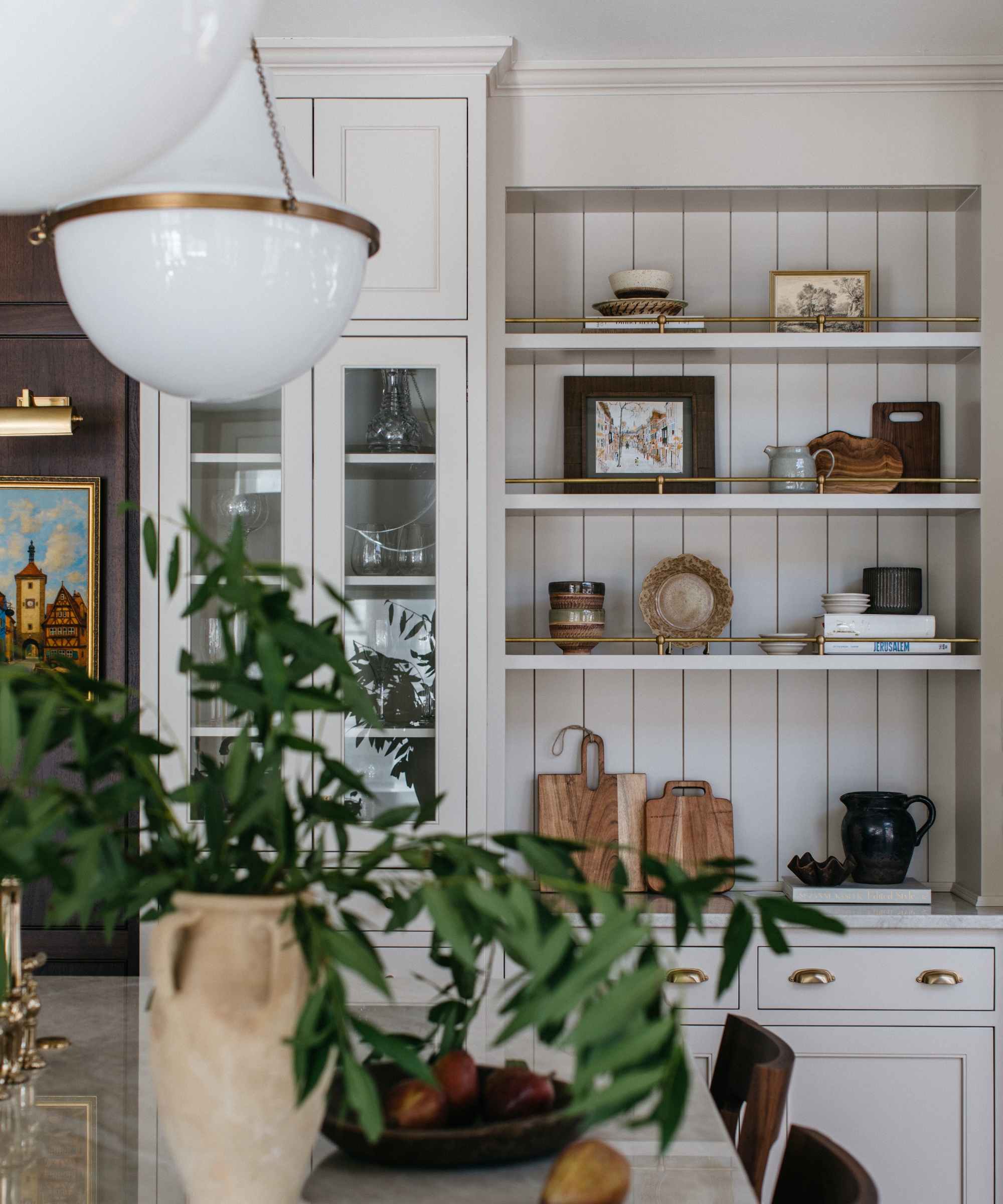Une cuisine blanche avec des étagères ouvertes remplies d'œuvres d'art et de décorations collectionnées