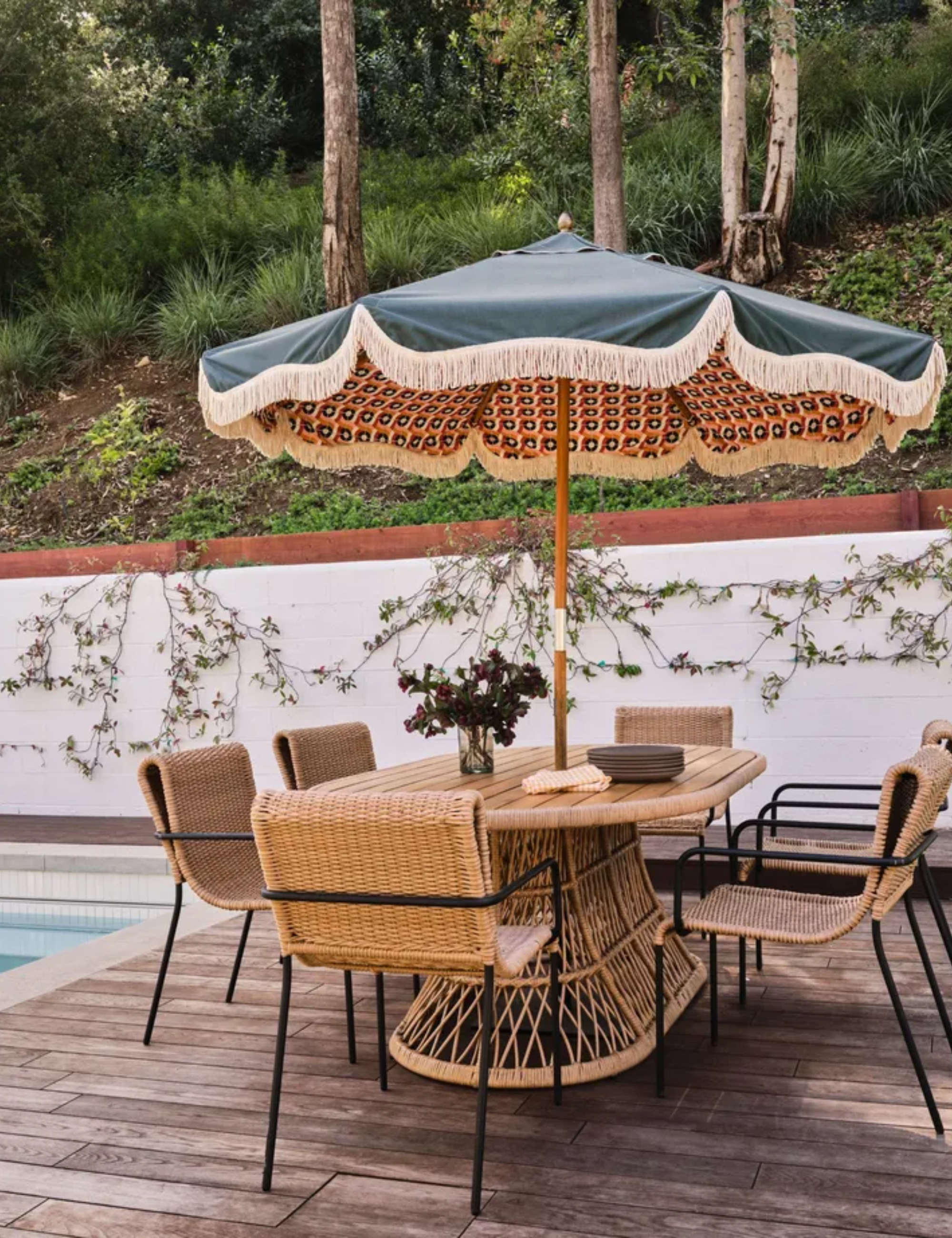 terrasse au bord de la piscine avec parasol et meubles en rotin