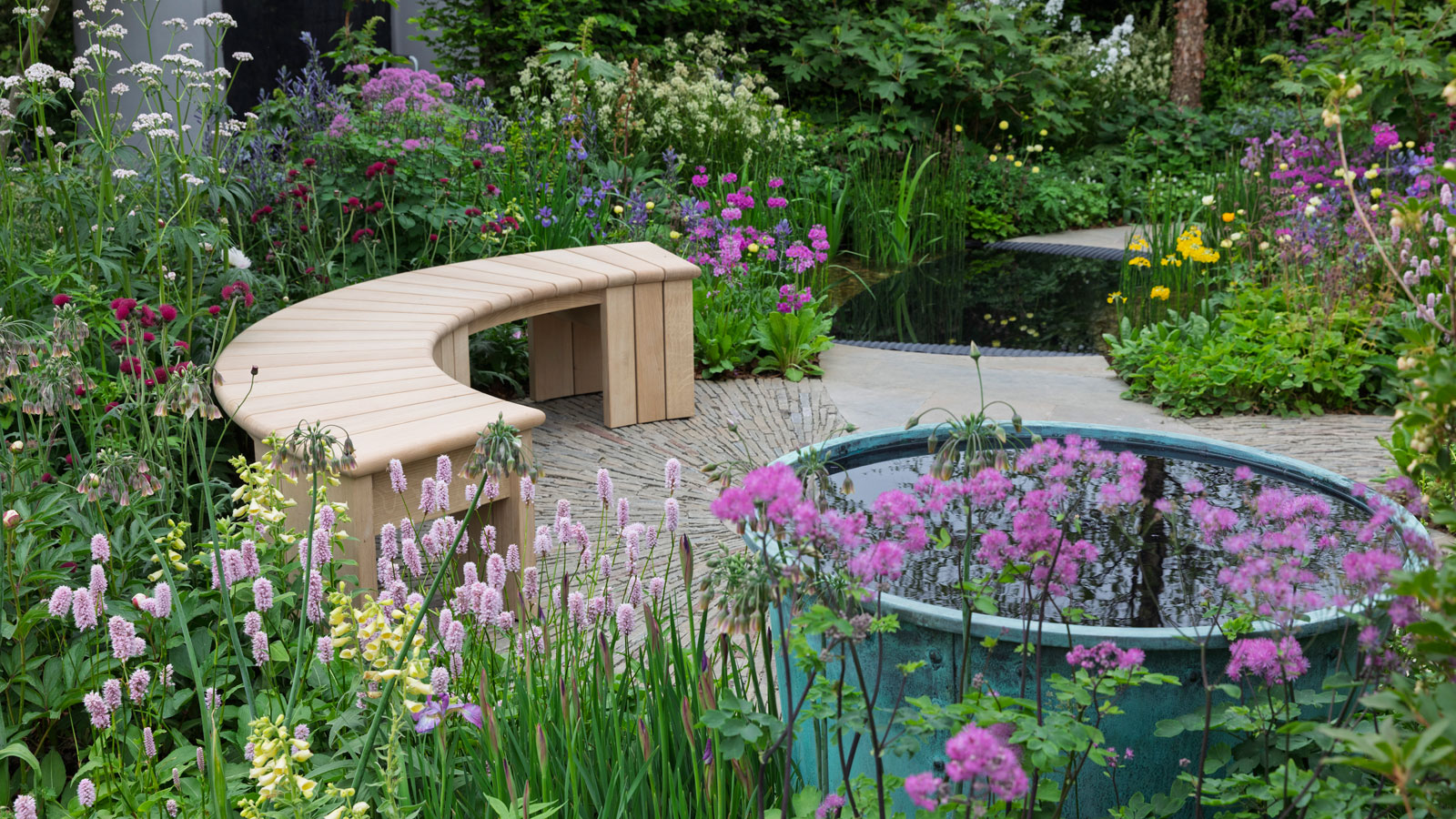 jardin fleuri avec banc et jeu d'eau