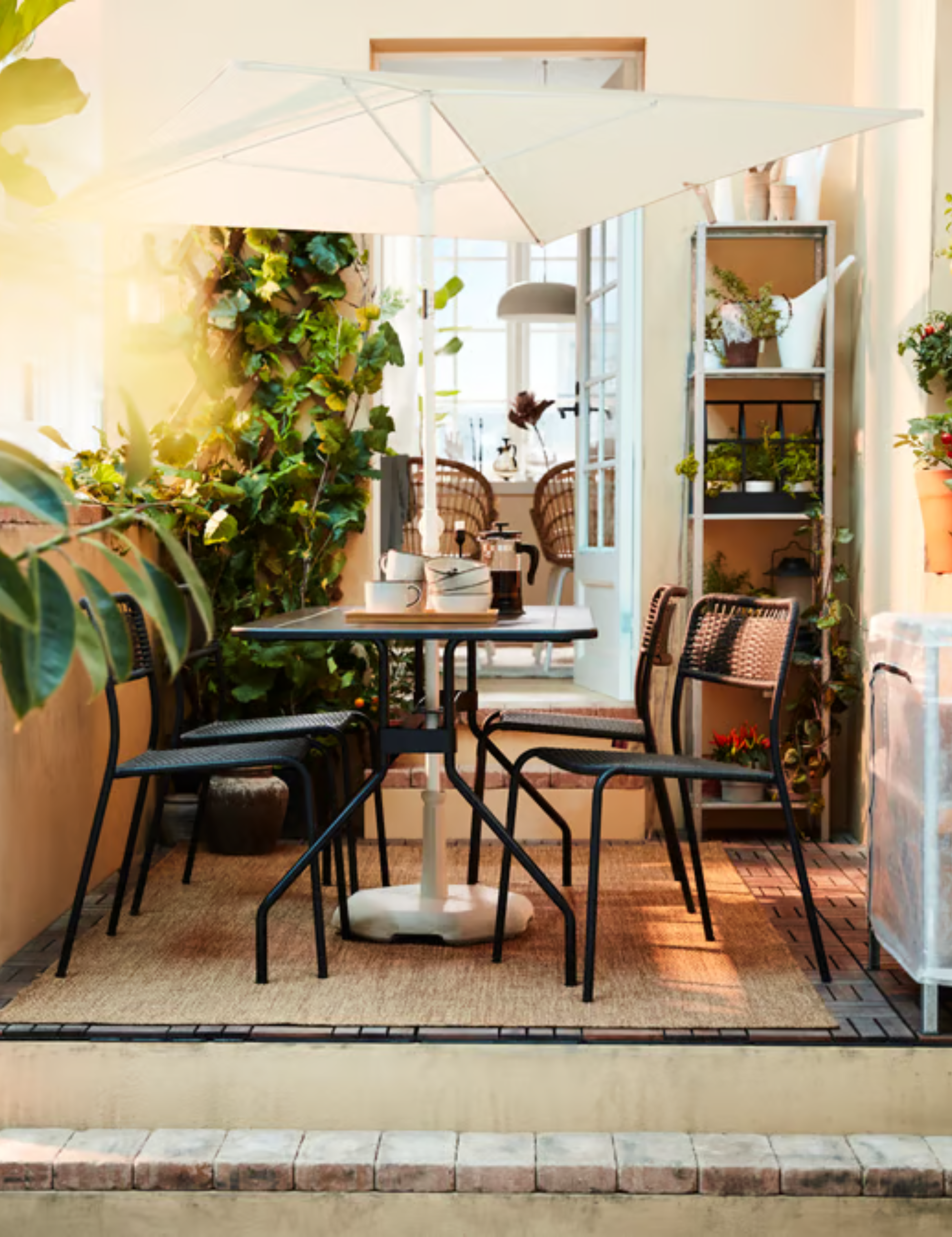 L'EFTP&Ouml; parasol ombrageant un charmant patio en fer noir situé au sommet d'un petit patio agrémenté de plantes en pot