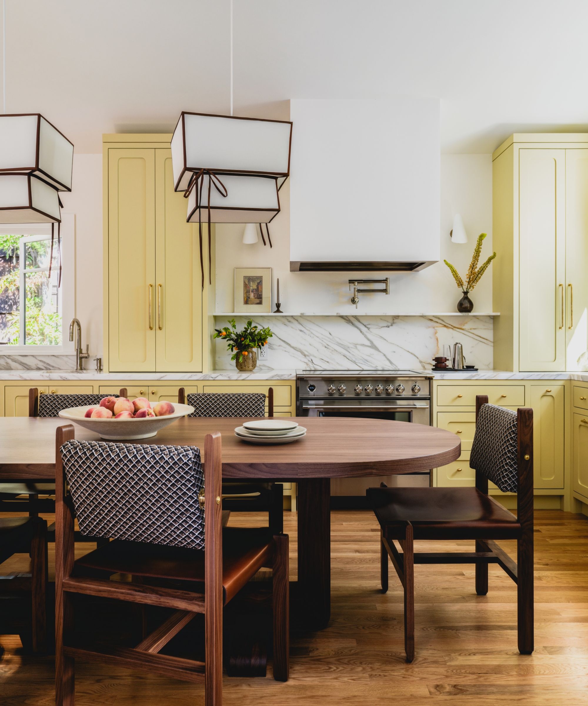 Une cuisine jaune avec des comptoirs en marbre, une table en bois et une cuisinière en acier inoxydable